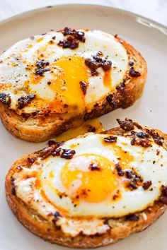 two pieces of bread with an egg on top are sitting on a plate next to each other