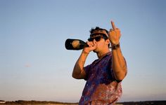 a man standing on the beach drinking from a bottle