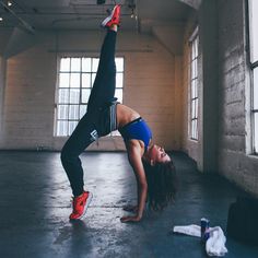 a woman is doing a handstand in an empty room with red shoes on