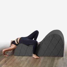 a woman laying on top of a large gray pillow in the middle of a room