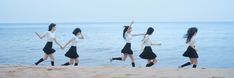 four women in black and white dresses are running on the sand by the water's edge