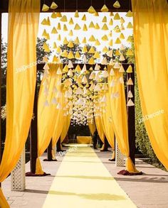 an outdoor ceremony with yellow draping and hanging decorations