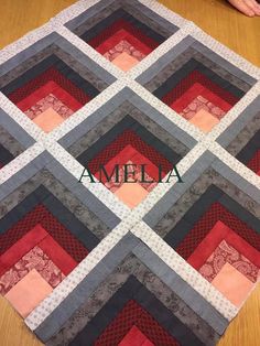 a close up of a quilt on a wooden table with the word amela in front of it