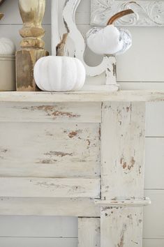 an old white fireplace mantel with pumpkins and other decorative items on the mantle