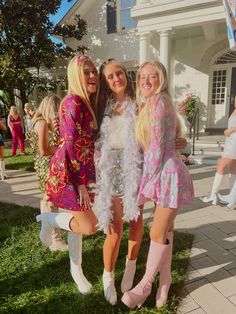 three girls dressed in pink and white posing for the camera with one girl wearing a feather boa around her neck