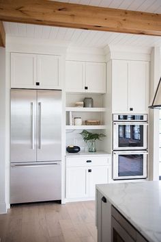 a kitchen with white cabinets and stainless steel appliances in the center, along with an island