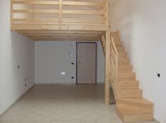 an empty room with stairs leading up to the second floor and another door on the other side