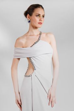 This elegant gown is crafted from beaded crepe fabric, making it perfect for gala and evening events. Its revealing design adds a touch of sophistication, without sacrificing comfort. Its luxurious material and intricate beading will make you stand out in any formal setting. This long crepe asymmetrical neckline dress is featuring beadings on the neckline. This design has draping on the waist, an open side waist with beadings. A high side slit that made the slim cut silhouette, more appealing to Asymmetrical Dress Formal, Gemy Maalouf, Asymmetrical Neckline Dress, Intricate Beading, Dress Asymmetrical, Neckline Dress, Asymmetrical Neckline, Fabric Making, Gowns Of Elegance