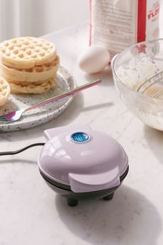 a waffle maker sitting on top of a counter next to other food items and utensils