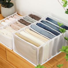 an open drawer with several pairs of folded clothes in it on top of a wooden table