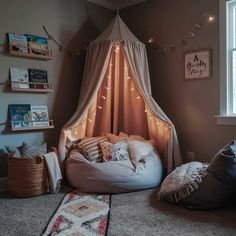 a bedroom with a canopy bed and pillows on the floor, lights strung from the ceiling