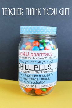 a jar filled with colorful candy sitting on top of a yellow table next to a blackboard