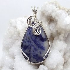 This listing is for a Sodalite from Namibia necklace wire-wrapped  in .925 sterling silver wire. Each piece of jewelry is a handcrafted, unique, one-of-a-kind piece of art.  The cabochon was shaped and polished by us from a rough gemstone into the unique piece of jewelry you see today.Details:handmade wire-wrapped cabochon pendantgemstone: Sodalitecarats: 31.05 ctcolor: blue, whitedimensions: approx 27 X 51 mm or 1.06 X 2.01 inches (large sized)A chain or cord of your choice is included with pur Wire Wrapped Sodalite Jewelry As Gift, Wrapped Cabochon, Handmade Silver Sodalite Necklaces, Adjustable Blue Wire Wrapped Crystal Necklace, Handmade Sodalite Healing Necklace, Spiritual Agate Necklace Wire Wrapped, Wire Wrap Cabochon, Handmade Wire Wrapped, Cabochon Pendant