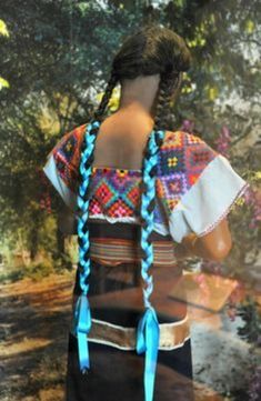 a woman with long braids standing in front of a tree and water reflection on the wall