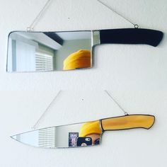 two mirrors hanging on the side of a wall, one with a knife and yellow hat