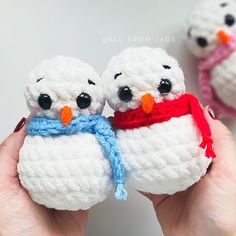 two small crocheted snowmen are held in their hands