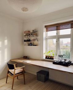 an empty desk in the corner of a room with a window and shelves on the wall