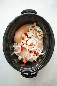 an overhead view of onions and carrots in a slow cooker