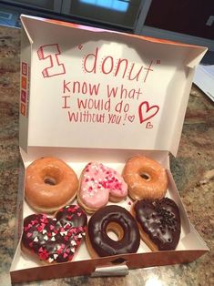 a box filled with donuts sitting on top of a counter next to a sign