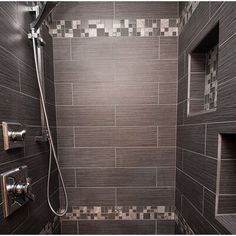 a bathroom with tiled walls and flooring in grey tones, including the shower head