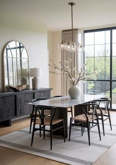 a dining room table with four chairs and a vase on top of it in front of a large window