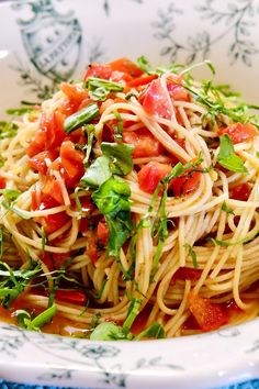 pasta with tomato sauce and herbs in a white bowl on a blue tableclothed cloth