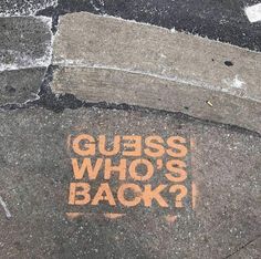 the sidewalk has graffiti written on it that says guess who's back? in orange