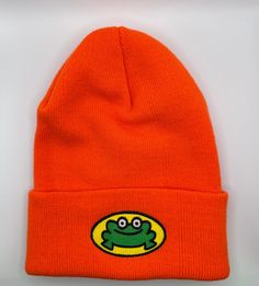 an orange beanie with a green frog on it