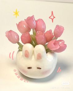 a small white vase with pink flowers in it's mouth on a table top