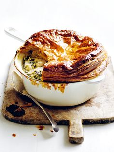 a baked dish with broccoli and cheese on a cutting board next to a spoon