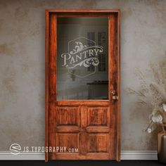 a wooden door with the words pantry on it in front of a vase filled with flowers