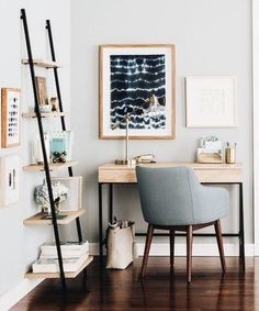 a desk and chair in a room with pictures on the wall above it, next to a ladder