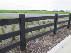 a black wooden fence next to a road