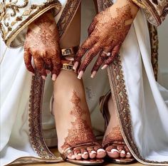 the legs and feet of a bride with henna tattoos