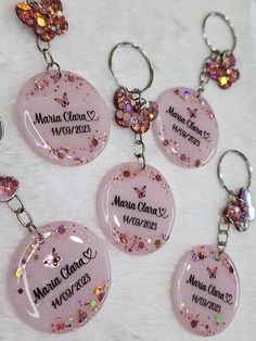 six personalized key chains are shown with pink and purple glitters on them,