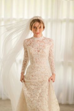 a woman in a wedding dress with a veil on her head is posing for the camera