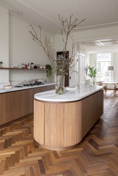 a kitchen with wood flooring and white counter tops, along with a center island