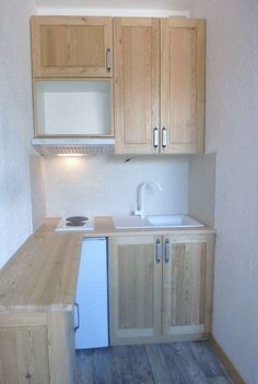 an empty kitchen with wooden cabinets and white appliances on the counter top, next to a sink