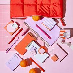 an overhead view of various office supplies including notebooks, pencils and oranges