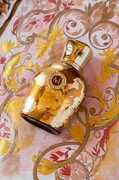 a gold flask bottle sitting on top of a pink and yellow floral table cloth