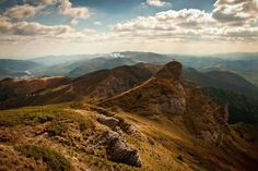 the view from the top of a mountain looking down at some hills and mountains in the distance