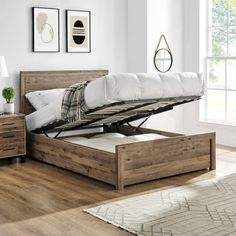 a bed with a wooden frame and mattress on top of it in a room next to a window