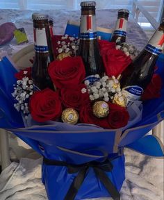 a bouquet of red roses and chocolates in a blue wrapper with bottles of beer