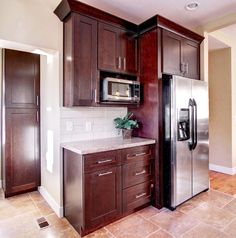 a kitchen with wooden cabinets and stainless steel refrigerator freezer combo in the center, along with tile flooring