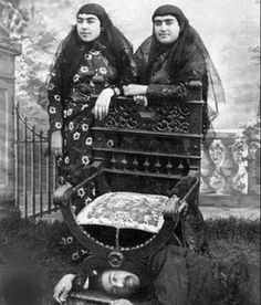 an old photo of two women standing next to a baby carriage in front of a fence