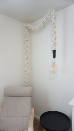 a chair and table in a room with a light bulb hanging from it's ceiling