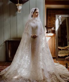 a woman in a white wedding gown and veil standing on a rug with an animal skull hanging from the wall behind her