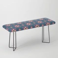 an upholstered bench with metal legs and floral fabric on it, against a white background