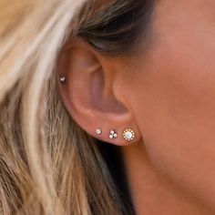 a close up of a woman's ear with three small white stones on it