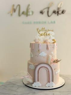 a pink and gold cake with a rainbow on top